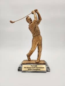 A golf trophy featuring a golfer in mid-swing, mounted on a black base with a gold plaque that reads "PUCCNR 7th Annual Golf Tournament 2024 Champions."