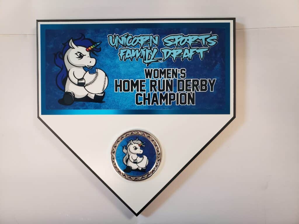 A plaque shaped like a baseball home plate featuring a cartoon unicorn holding a baseball, with text that reads "Unicorn Sports Family Draft Women's Home Run Derby Champion."