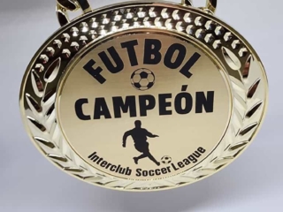 A gold medal with a chain, inscribed with 'FUTBOL CAMPE&Oacute;N' and 'Interclub Soccer League,' featuring a soccer player silhouette and a soccer ball design.