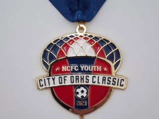 A custom medal featuring the design "NCFC Youth City of Oaks Classic" with a soccer theme, set against a navy, red, and white background, and attached to a blue ribbon.