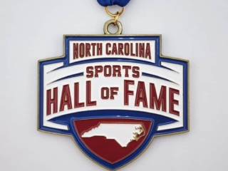 A custom medal with the inscription "North Carolina Sports Hall of Fame" featuring a map outline of North Carolina, attached to a blue ribbon.