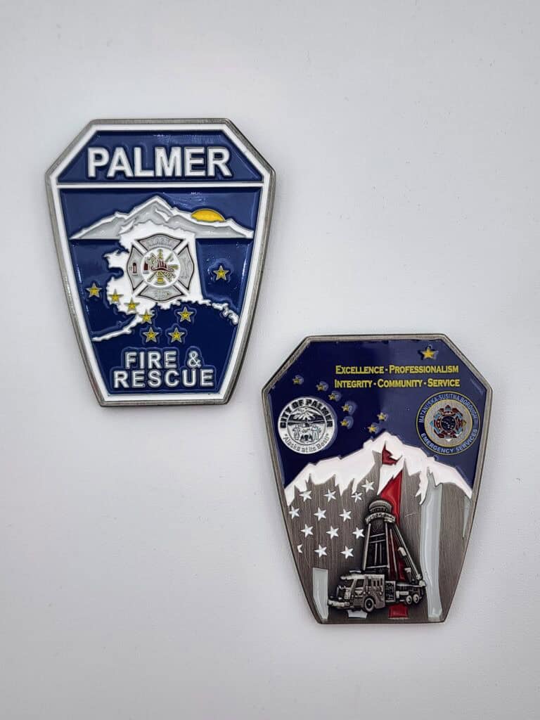Two fire department badges, one labeled 'Palmer Fire &amp; Rescue' with mountains and stars, and the other featuring imagery of mountains, a fire truck, and phrases like 'Excellence,' 'Professionalism,' and 'Community.'