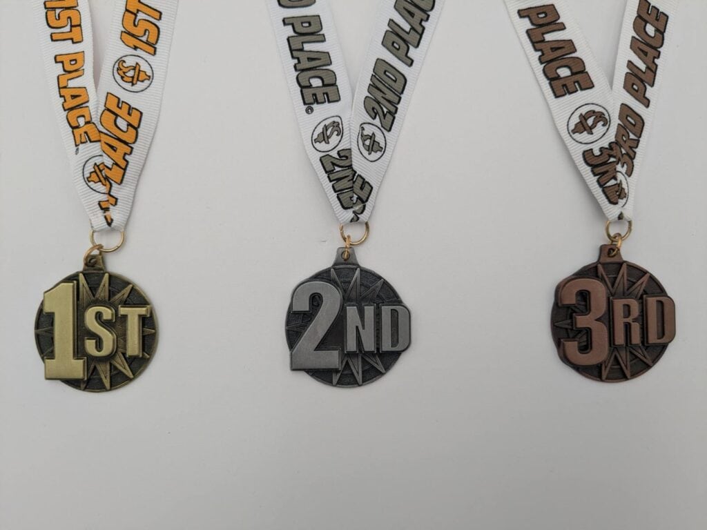 Three sports medals with ribbons labeled "1st Place," "2nd Place," and "3rd Place," featuring gold, silver, and bronze finishes.