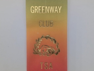 A vertically gradient award ribbon with text reading "THE GREENWAY CLUB TSA PERSONAL BEST" and a laurel design in gold lettering.