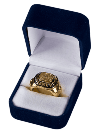 A gold championship ring with an engraved top, resting in a blue velvet ring box with a white interior.
