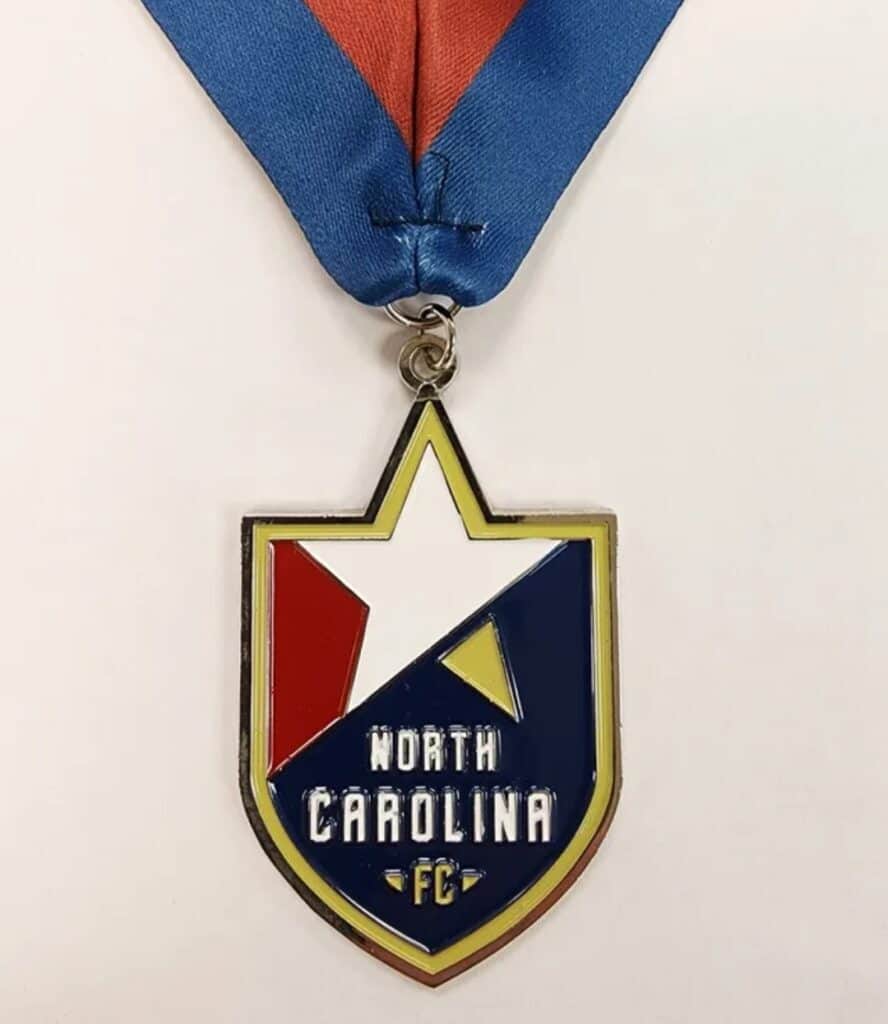 Custom medal featuring the North Carolina FC logo with a star design, attached to a blue and red ribbon.